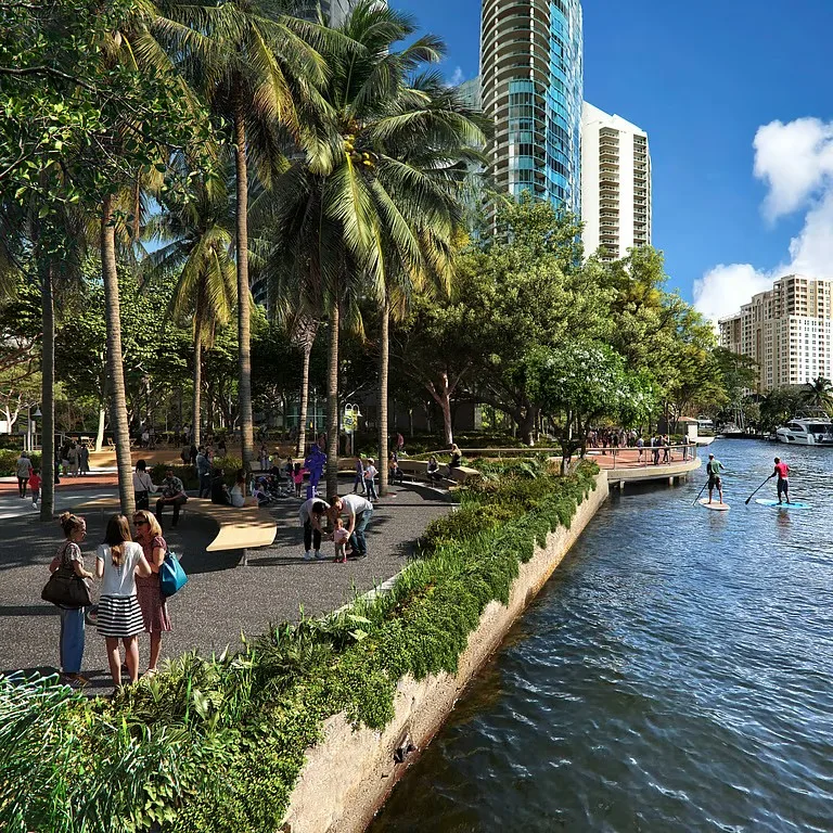 Fort Lauderdale Riverwalk at Huizenga Park — brick promenade, palm trees, and yacht along the New River with downtown condo towers